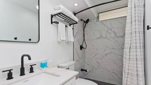 A modern bathroom with a white sink, black faucet, and a shower with a white curtain. - Aloha Suite Near the Sea IV, 3 Block Walk to Beach (Honolulu)