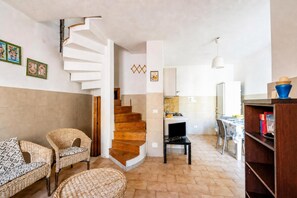 Ein modernes Interieur mit einer Wendeltreppe, Korbmöbeln, einer Küchenzeile und einem Essbereich.