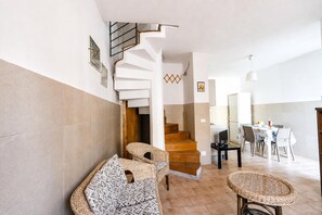 A modern interior with a staircase, wicker furniture, and a dining area.