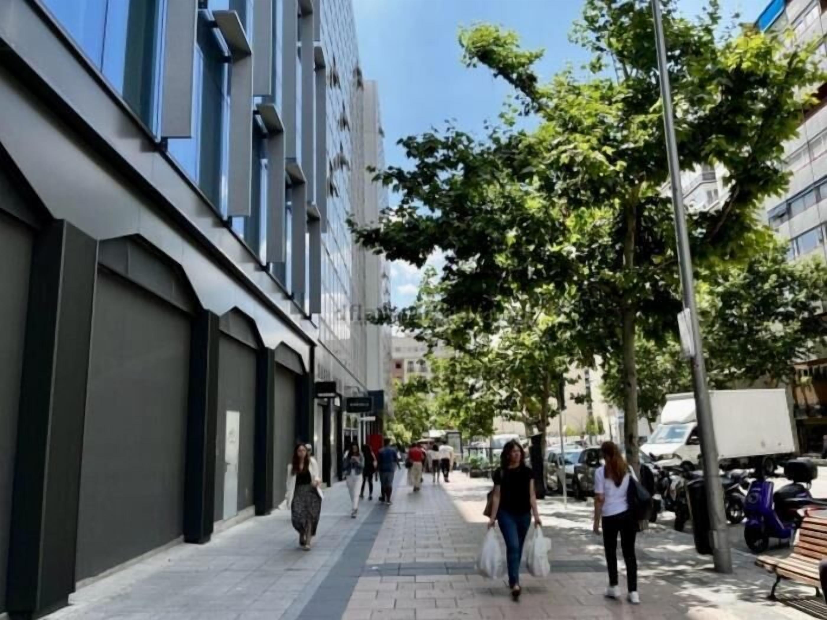 A city street with pedestrians, parked vehicles, and buildings.