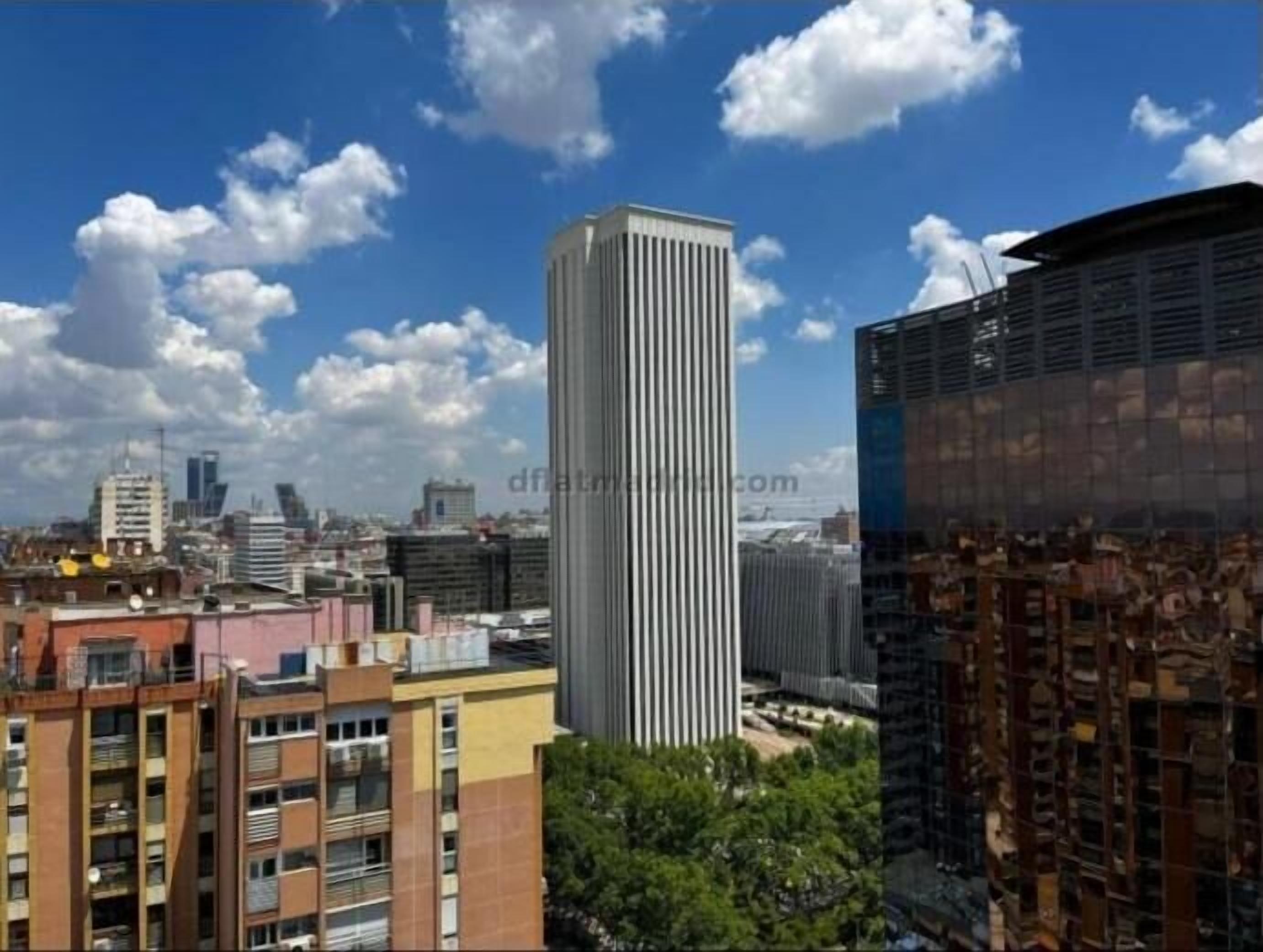 Un immeuble de grande hauteur au design moderne, entouré d’autres constructions urbaines.