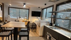 A compact kitchen with a dining area, a bed, and a TV mounted on the wall. - Chic Studio Loft with City Views (Madrid)