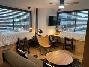 A modern hotel room with two beds, a desk, a chair, a round table, and a TV. - Chic Studio Loft with City Views (Madrid)