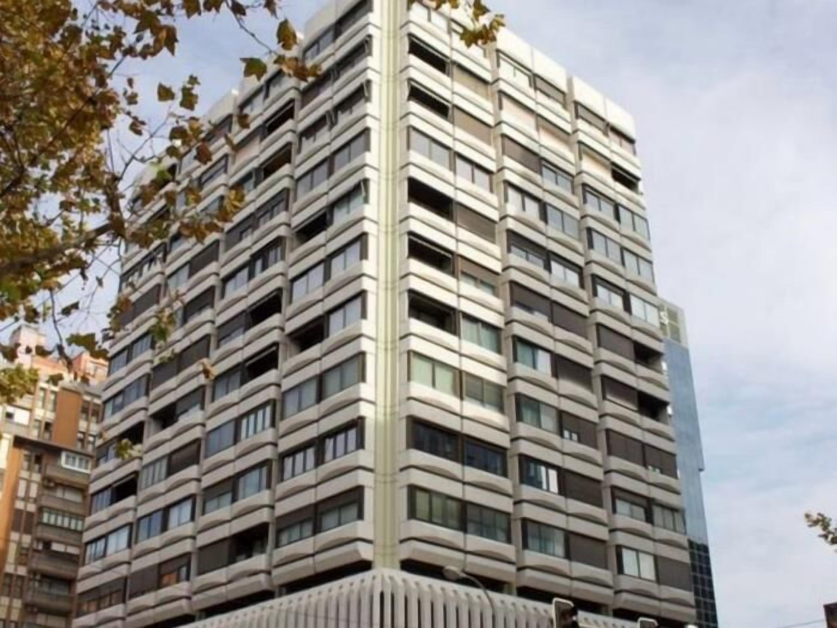 A high-rise building with a modern architectural design, featuring a grid of windows and balconies.