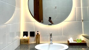 A modern bathroom with a round mirror, a white sink, and a granite countertop. - Lebak Bali Batu Mejan (Canggu)