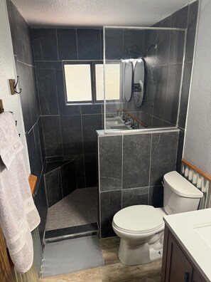 A compact bathroom with a shower enclosure, a toilet, and a sink.