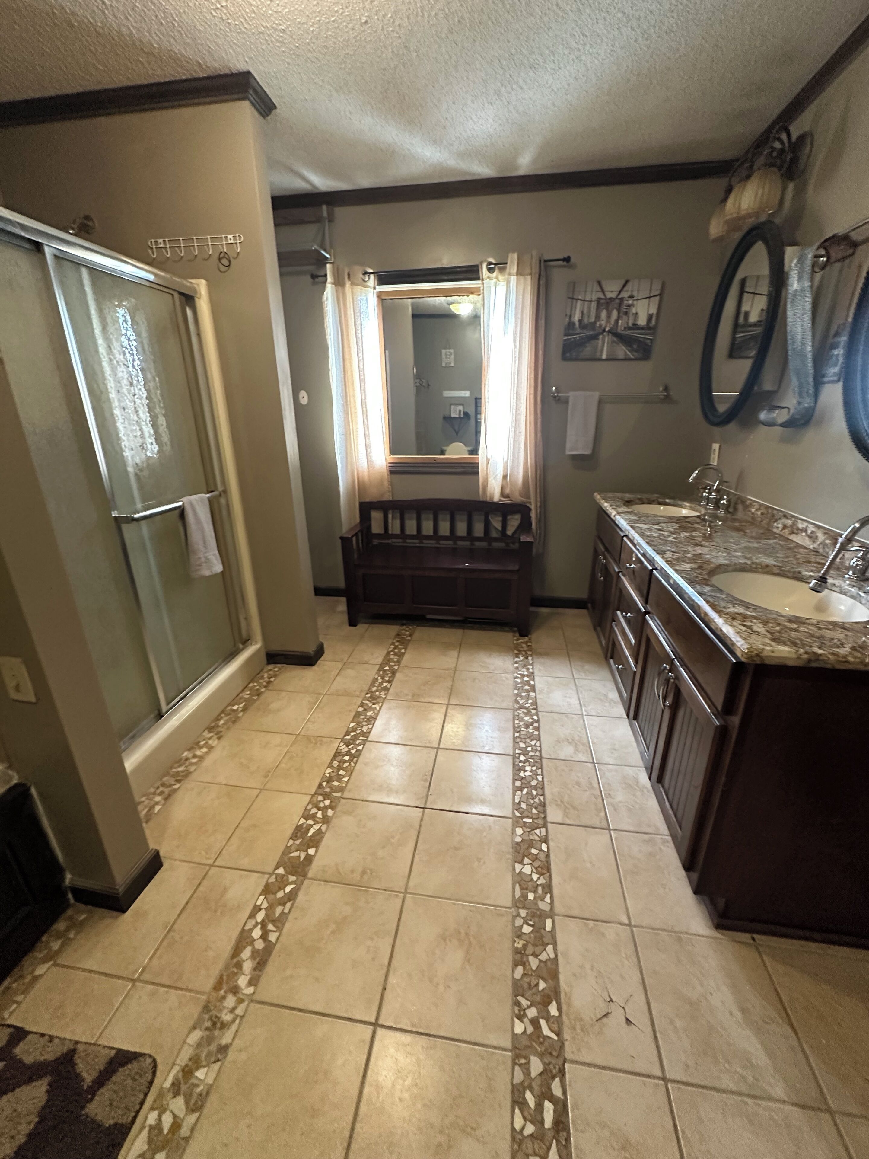 A bathroom with a shower, a vanity with a sink, and a bench.
