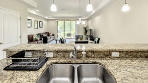 A modern kitchen with granite countertops, stainless steel sinks, and pendant lighting.