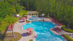 An aerial view of a resort with a large swimming pool, lounge chairs, and a gazebo.
