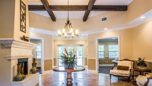 A spacious living room with a fireplace, a chandelier, and a round table.