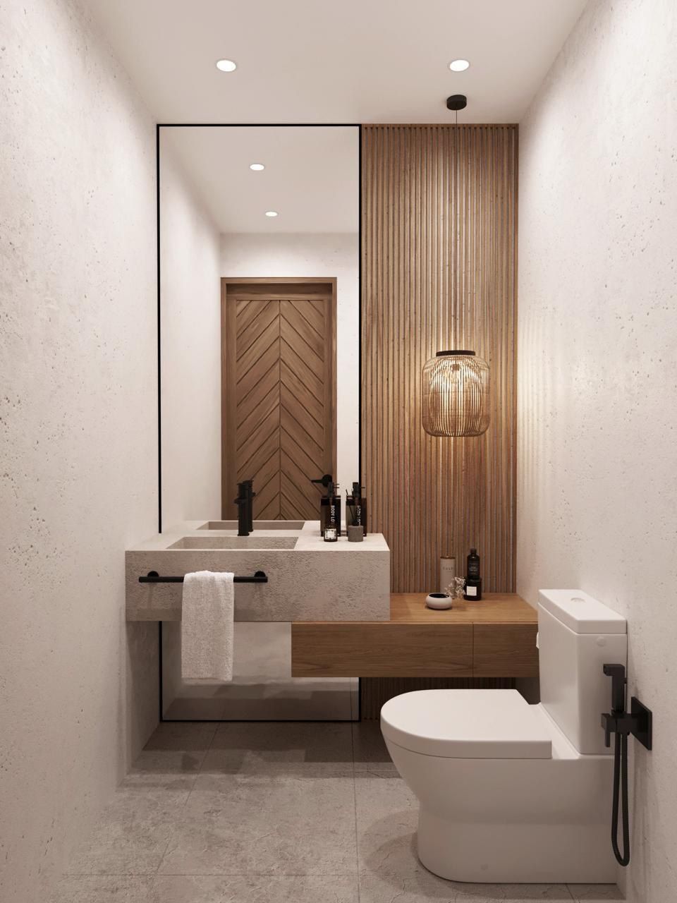 Une salle de bain moderne avec un grand miroir, un mur recouvert de panneaux en bois, un lavabo avec un porte-serviettes et des toilettes.