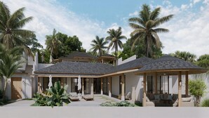 Een moderne villa met een overdekt terras, grote ramen en een tropische tuin.
