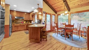 A spacious kitchen with wooden cabinets, a large island, and a dining area with a table and chairs.