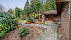 A wooden house with a stone pathway leading to a porch with outdoor furniture.