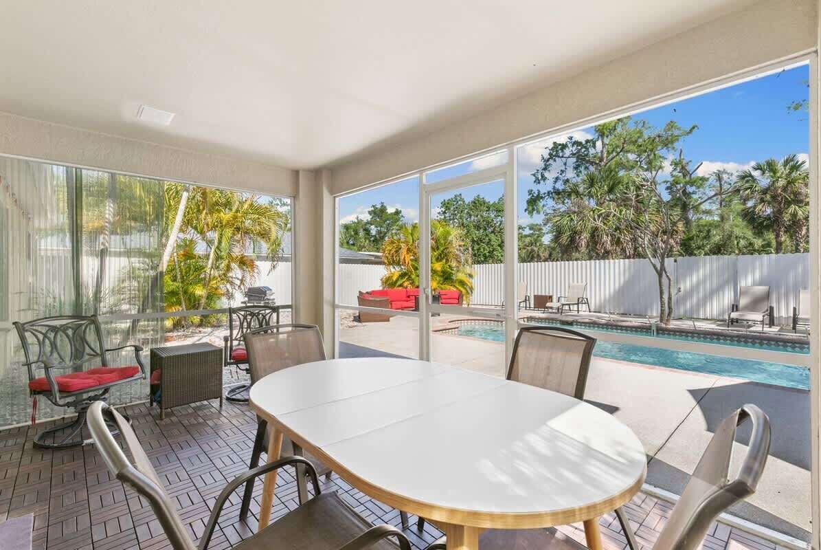 Eine sonnendurchflutete Terrasse mit Pool, Sitzgelegenheiten im Freien und großen Fenstern mit Blick auf den Poolbereich.