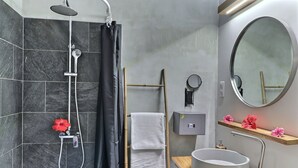 Un baño moderno con ducha, lavamanos, espejo y toallero.