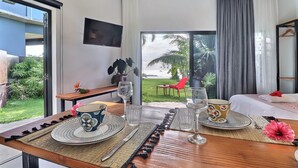 Un comedor con una mesa dispuesta para dos personas, un televisor montado en la pared y vistas al jardín a través de la ventana.