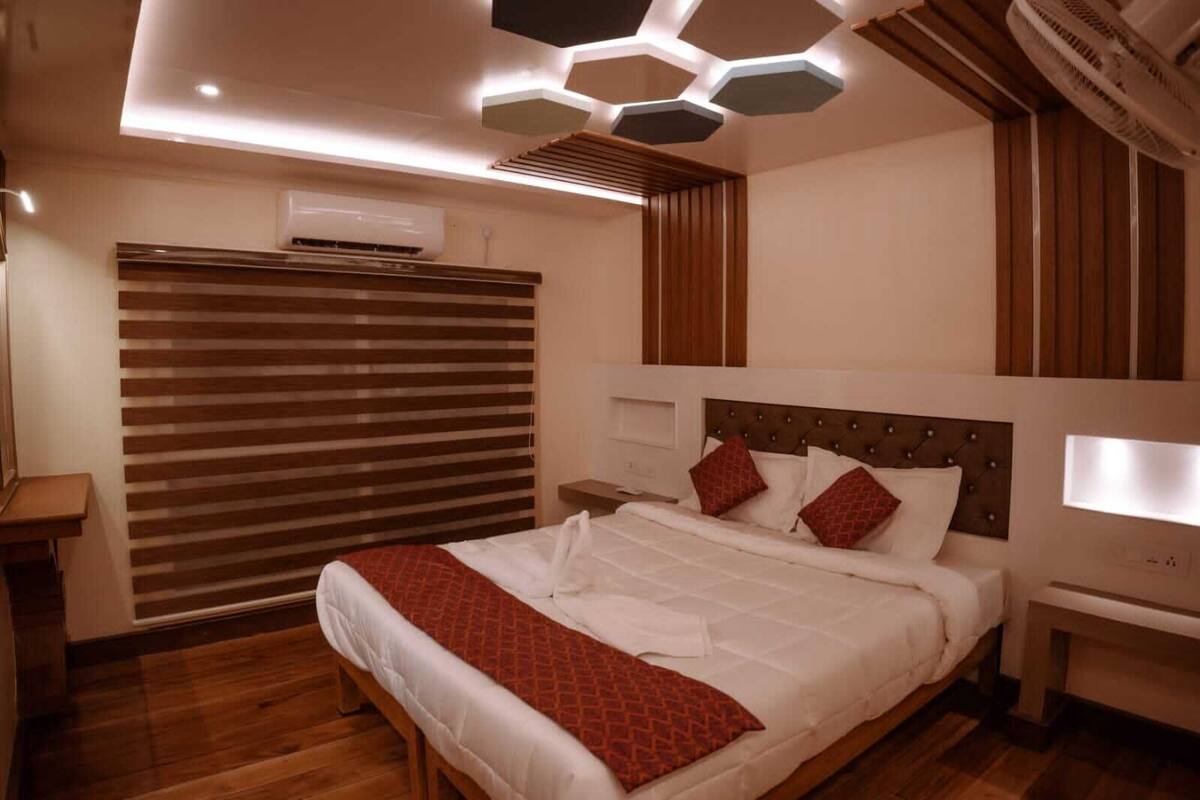 Een moderne slaapkamer met een groot bed, houten vloeren, een verstelbaar rolgordijn en een uniek, zeshoekig plafond.