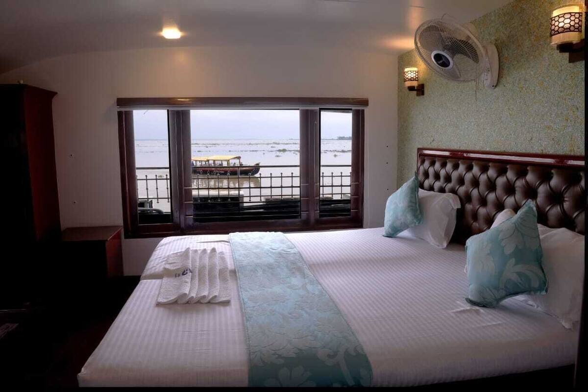 Hotelkamer met een groot bed, uitzicht op zee, een balkon en een ventilator.