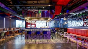 Un espace bar avec un comptoir, des tabourets et un coin salon rouge.