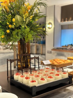 A buffet table with small dessert cups and a floral centerpiece. - Sanya Yalong Bay No.99 Resort Hotel (Sanya)