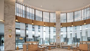 Eine geräumige Lobby mit hohen Decken, großen Fenstern und moderner Einrichtung.