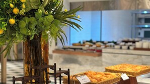 Ein reichhaltiges Buffet mit verschiedenen Speisen, darunter Gebäck und Desserts, auf einem Tisch angerichtet.