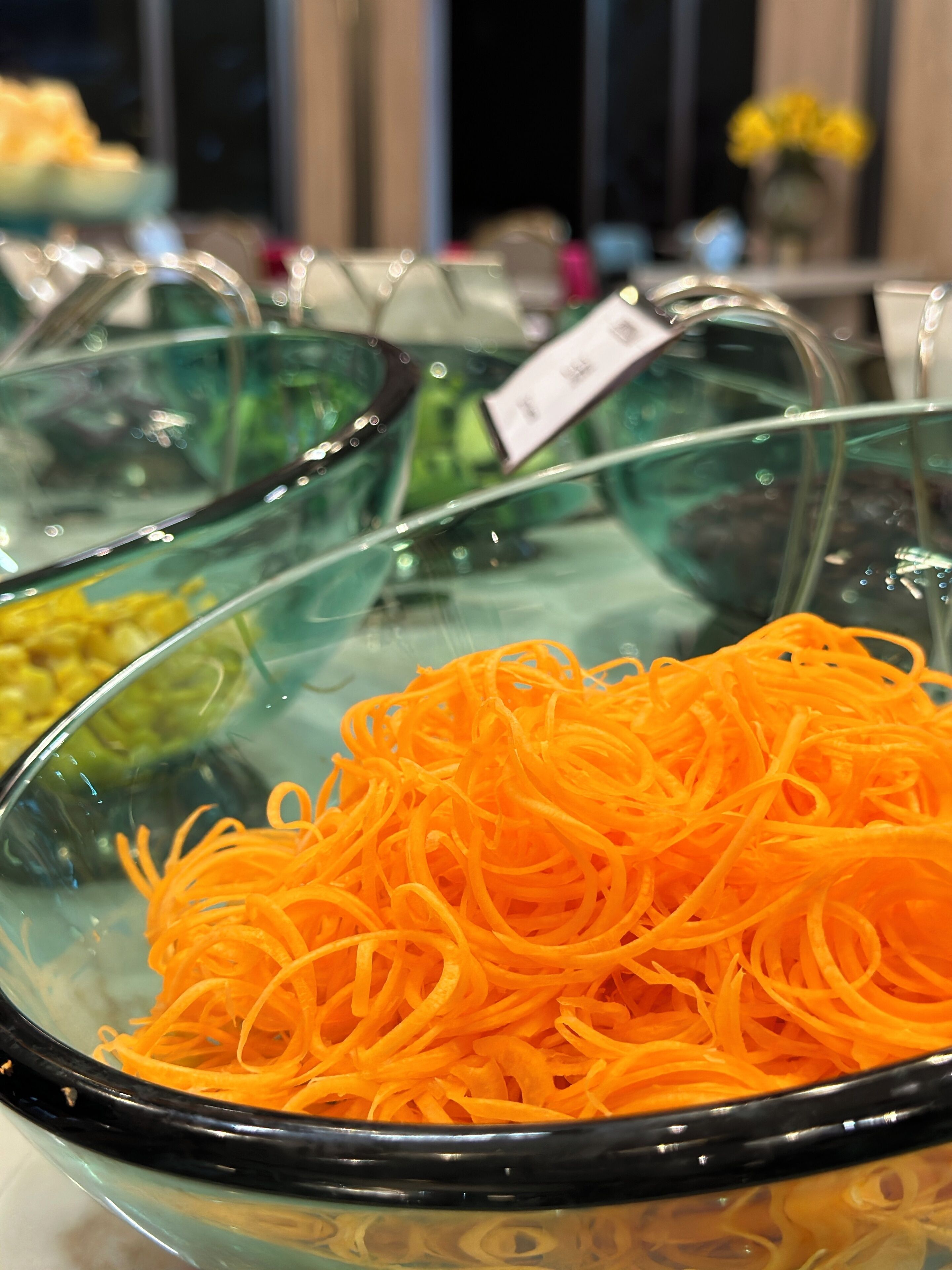 A buffet with various food items, including a bowl of shredded carrots.