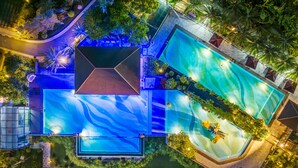 Eine Luftaufnahme eines Resorts mit mehreren Swimmingpools, einem überdachten Bereich und üppiger Bepflanzung.