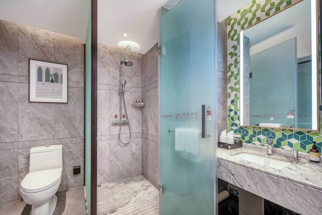 A modern bathroom with a glass shower enclosure, a marble sink, and a toilet.