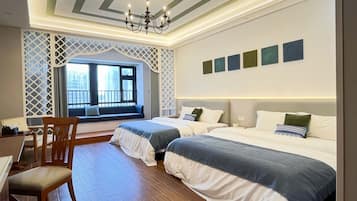 Habitación de hotel con dos camas, un escritorio y ventana con vistas a edificios.