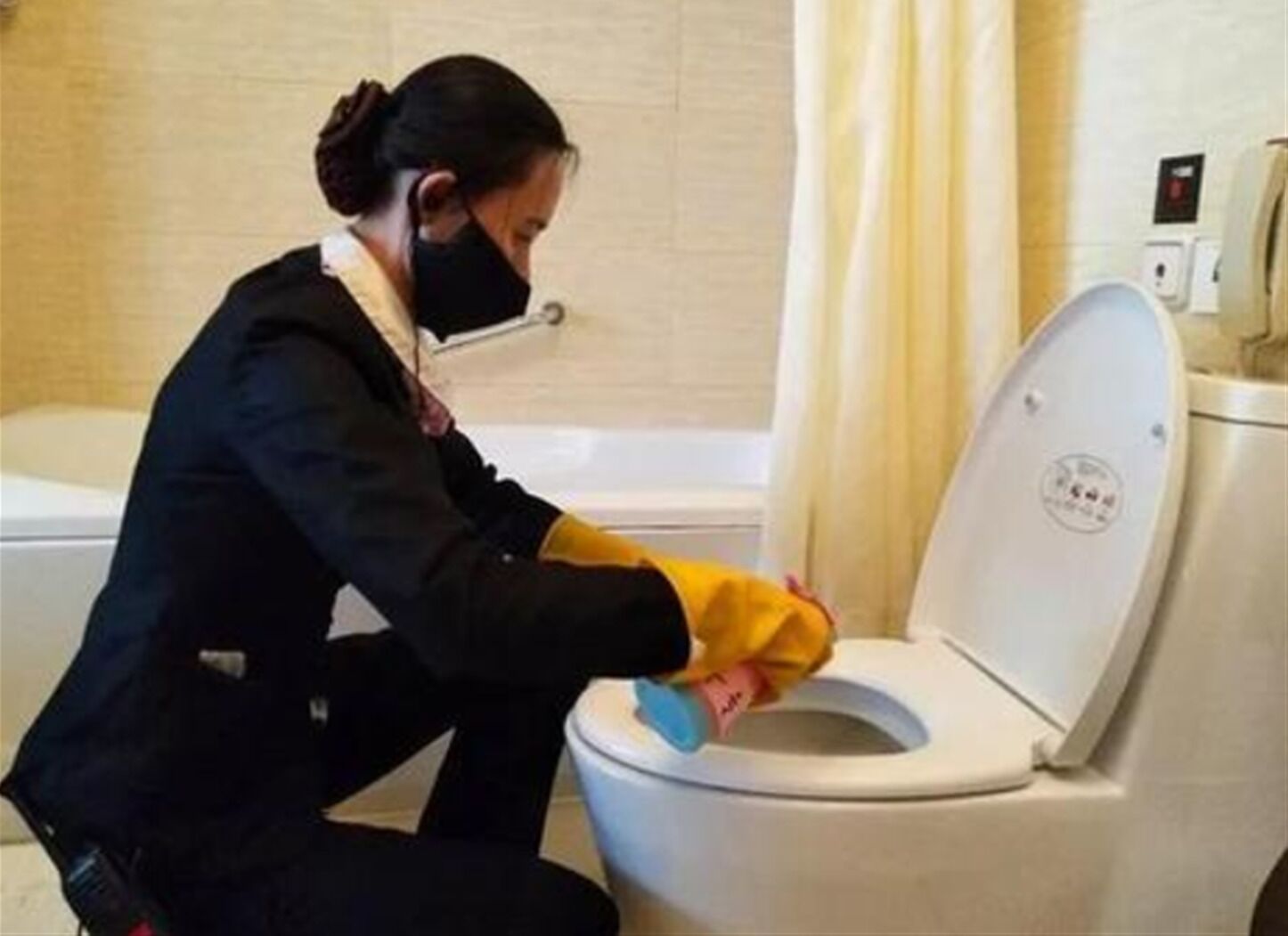 Une personne qui nettoie des toilettes avec un vaporisateur et un chiffon.