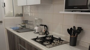 Een kleine keuken met een gasfornuis, magnetron en koffiezetapparaat.