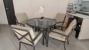 A round glass table with four chairs, a potted orchid, and a kitchen area with a sink and countertop. - 5 minutes from the Beach Club! Acapulco Diamante Apartment (Acapulco)