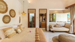 A bedroom with a large bed, a sofa, and a dining area. - Villa Jamu Bingin (Pecatu)
