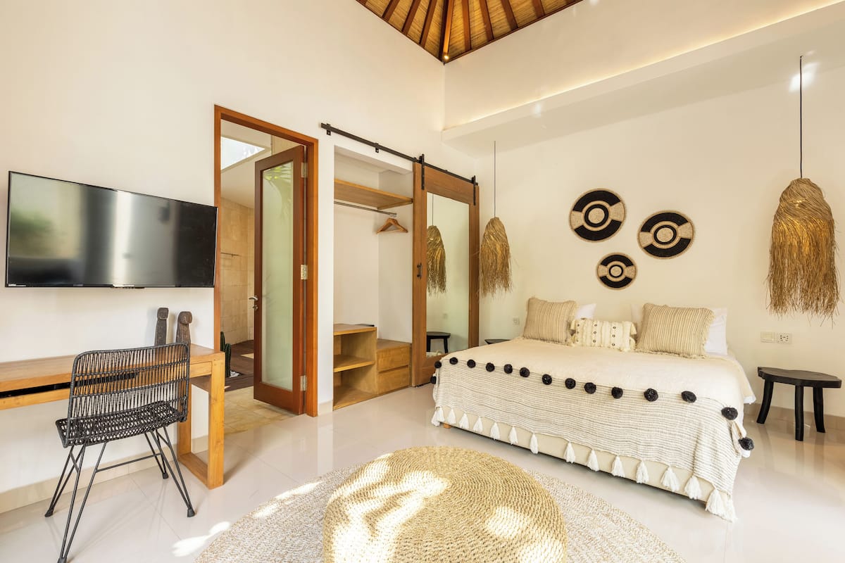 Een moderne slaapkamer met een bed, een bureau en een televisie.