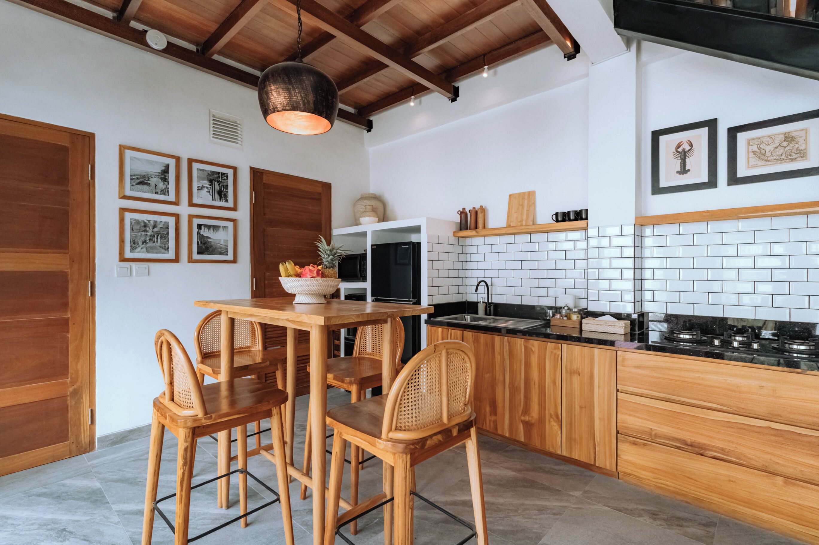 Une cuisine moderne avec des meubles en bois, un pare-feu en carreaux blancs et un coin repas comprenant une table et des chaises en bois.