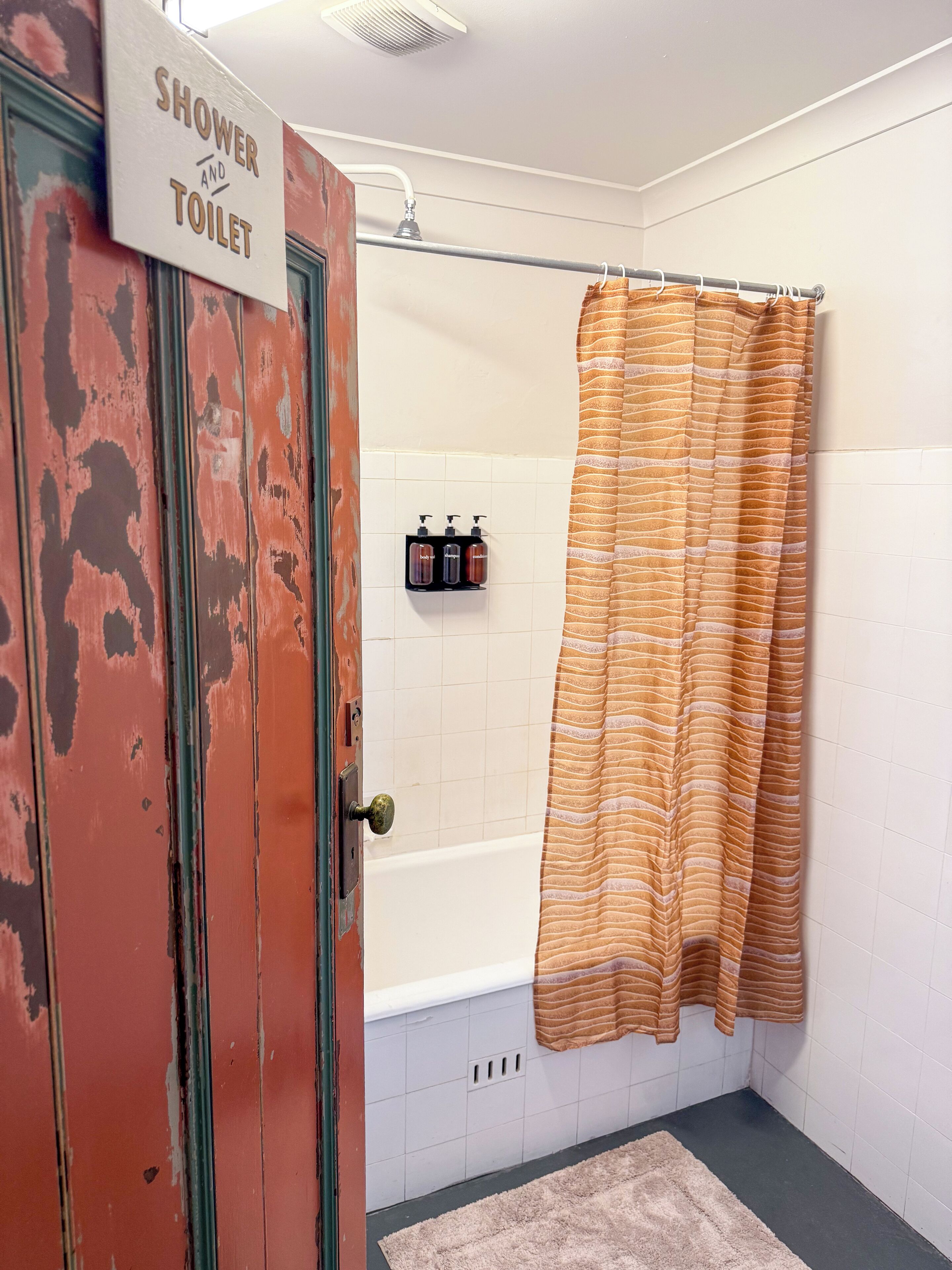 A bathroom with a shower curtain, a bathtub, and a sign indicating the presence of a shower and toilet.