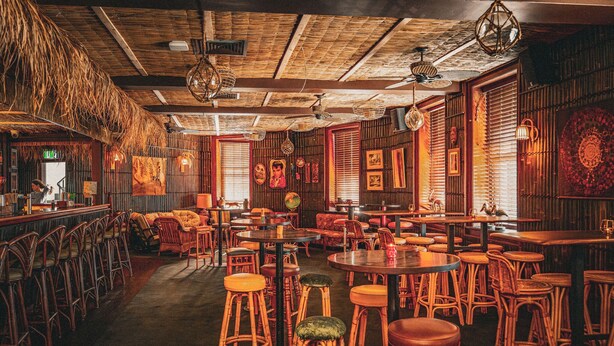 Un restaurante con mobiliario de madera, luces colgantes y cuadros en las paredes.