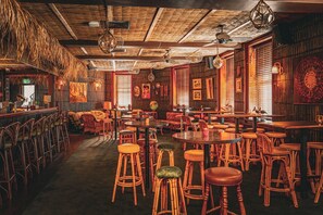 Un restaurant avec des meubles en bois, des luminaires suspendus et des tableaux encadrés aux murs.