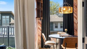 A dining area with a round table, two chairs, a hanging light fixture, and a view of the outside. - Kay’s Perch • Modern 1BR Corner Retreat (Nashville)