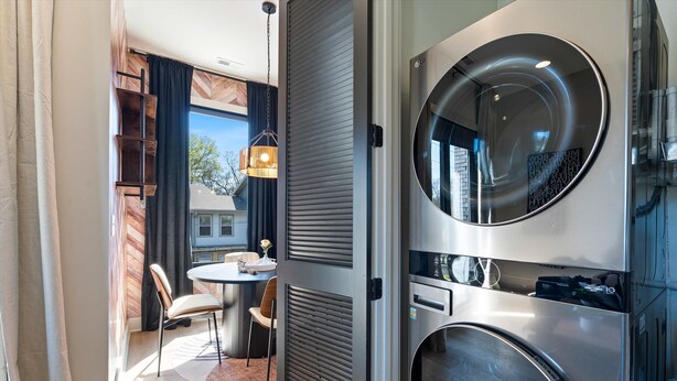 A modern kitchen with a built-in oven, a round mirror, and a dining area with a table and chairs. - Kay’s Perch • Modern 1BR Corner Retreat (Nashville)