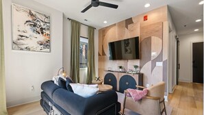 A modern living room with a sofa, a chair, a TV, and a kitchen area.
