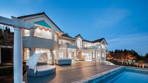 Une maison luxueuse dotée d’une piscine, d’un espace salon extérieur et d’un patio bien éclairé.