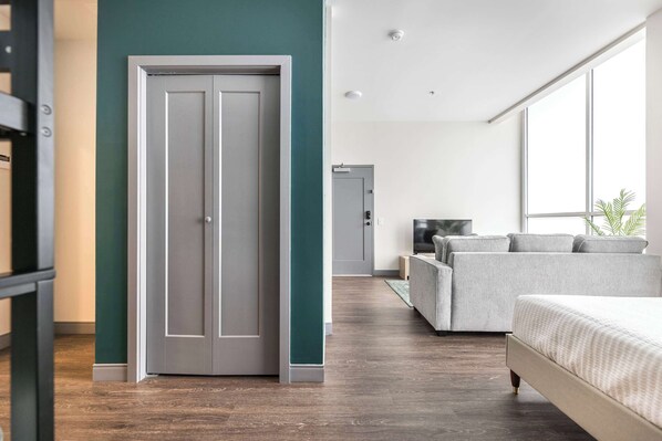 Un dormitorio moderno con cama, sofá gris y televisor.