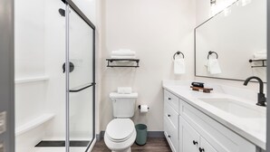 A modern bathroom with a glass shower enclosure, a toilet, a sink with a mirror, and a vanity with drawers. - Cozy Stay Next To Atrium Hospital | Walk Score 74; Mercer Music at Capricorn – ~12-minute walk (0.6 miles) (Macon)