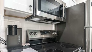 A modern kitchen with a stainless steel stove, microwave, and refrigerator. - Cozy Stay Next To Atrium Hospital | Walk Score 74; Mercer Music at Capricorn – ~12-minute walk (0.6 miles) (Macon)