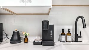 A modern kitchen with a coffee maker, a sink, and two soap dispensers. - Right Next To Atrium Hospital | ADA-Friendly Stay (Macon)