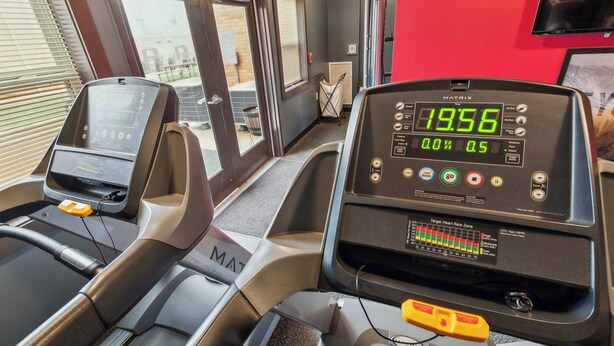 A treadmill with digital display, control panel, and safety features.
