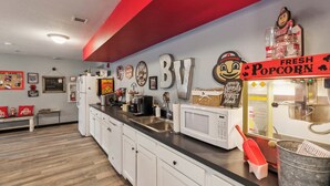 A kitchen with white cabinets, a black countertop, a microwave, a popcorn machine, and various decorations on the wall. - Modern Retreat Near Campus & Local Trails (Mansfield)